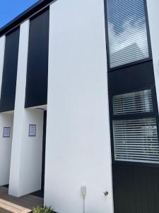 a white and black building with a black door at Colombo Executive Apartments in Christchurch