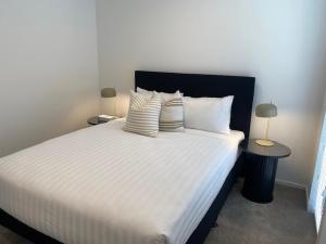 a bedroom with a large bed with white sheets and pillows at Colombo Executive Apartments in Christchurch