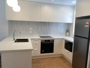 a kitchen with white cabinets and a stainless steel refrigerator at Colombo Executive Apartments in Christchurch +5 photos