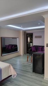 a bedroom with purple pillows and a bed and a couch at Hostal Imperio la Kennedy in Quito