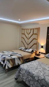a bedroom with two beds and a headboard at Hostal Imperio la Kennedy in Quito