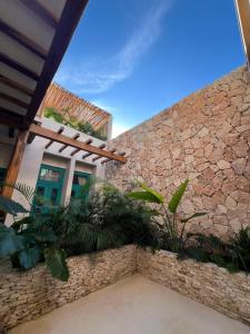 a building with a stone wall with plants in front at T'uut' Hotel in El Cuyo
