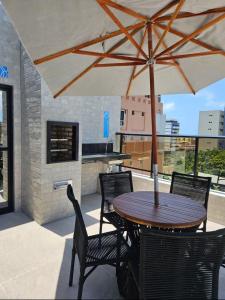 a table and chairs with an umbrella on a patio at Flat Azzure 205 in Cabedelo