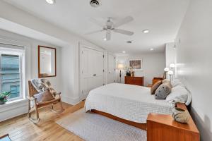 a white bedroom with a bed and a chair at Moore on Main in Abingdon