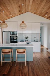 a kitchen with white cabinets and a blue island with two chairs at 3 Acres by the Moyne in Port Fairy