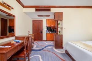 a bedroom with a bed and a desk and a kitchen at Domi Hotel in Siem Reap