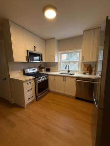 a kitchen with white cabinets and a sink and a stove at A home in Niagara falls- The Maple and Mist in Niagara Falls +11 photos