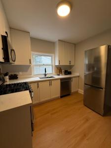 a kitchen with white cabinets and a stainless steel refrigerator at A home in Niagara falls- The Maple and Mist in Niagara Falls