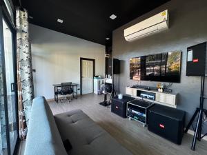 a living room with a couch and a tv at กัสเกรซ โฮมสเตย์ in Pak Chong