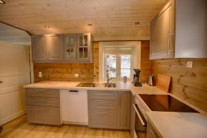 a kitchen with wooden walls and white cabinets and a sink at Modern Comforts, and Ski Access in Beitostøl