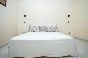 a white bed in a white room with a white mattress at Cabral residence in Guediawaye