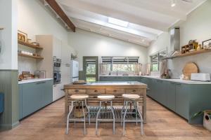 a large kitchen with a large island with bar stools at Mara Luxe Farm Stay 20 mins from Beach in Forster