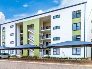 a large white building with umbrellas in front of it at Lagoon Aparthotel in Pretoria