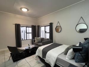 a bedroom with a bed and a chair and a couch at Lagoon Aparthotel in Pretoria +32 photos
