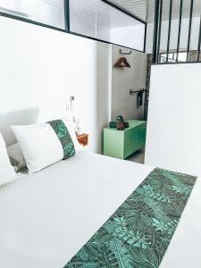 a bedroom with a large white bed with a green blanket at Vaikea Fare in Mahina