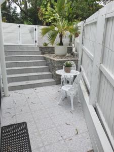 a patio with a table and a chair and stairs at Seaclusion at Byron in Byron Bay