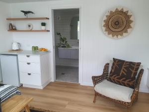 a living room with a chair and a kitchen at Seaclusion at Byron in Byron Bay +3 photos