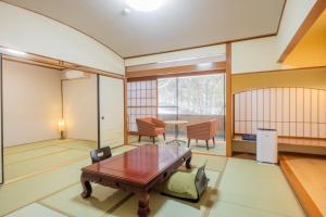 ein Wohnzimmer mit einem Holztisch und Stühlen in der Unterkunft 源泉の湯 福の屋 in Minakami
