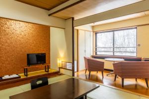 ein Wohnzimmer mit einem Tisch und einem Fernseher in der Unterkunft 源泉の湯 福の屋 in Minakami
