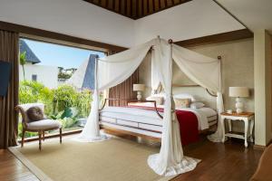 a bedroom with a canopy bed and a large window at Goya Boutique Resort in Ubud