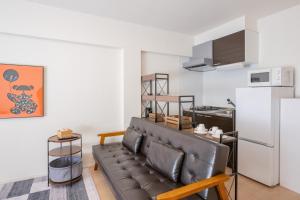 a living room with a couch and a refrigerator at Hotel HIRAKU RYUKYU -STYLE- in Naha