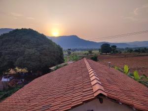 a roof of a house with the sunset in the background at Aalamaram Farm in Anchetti