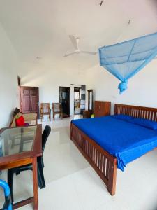 a bedroom with a bed with a blue bedspread and a table at Hotel Meer in Ambalangoda