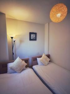 two beds in a room with a lamp and a chandelier at Uhome Ueno Hotel in Tokyo