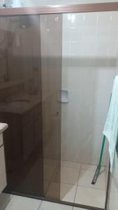 a shower with a glass door next to a sink at Apartamento suite central 72 in Franca