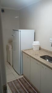 a kitchen with a white refrigerator and a sink at Apartamento suite central 72 in Franca