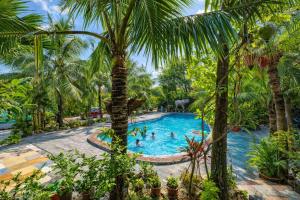 a pool with palm trees and people in it at Trang An Lighthouse Homestay in Ninh Binh