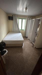 a small room with a bed with a window at Casa Zucchi in Itapema