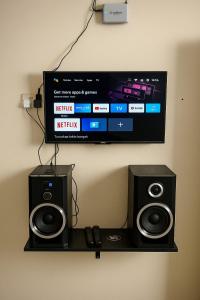 a tv on a wall with two speakers and a subwoofer at Locita Villa in Batu