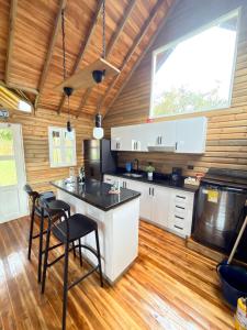 a kitchen with white cabinets and a island with stools at WOODEN HOUSE Hermoso alojamiento en Llanogrande Rionegro cerca a Medellín & Aeropuerto JMC in Rionegro +5 photos