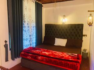 a bedroom with a bed with a red blanket on it at Downtown Lodge in Nuwara Eliya