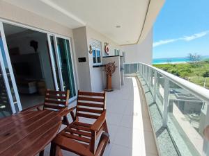 a balcony with a wooden table and two chairs at Sunset World, Le Bon Vivant Arraial do Cabo - Vista mar, ar condicionado e wifi in Arraial do Cabo