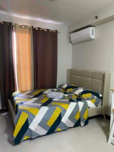 a bedroom with a bed with a yellow and blue comforter at Studio Stay at Saekyung Condominium in Lapu Lapu City +11 photos