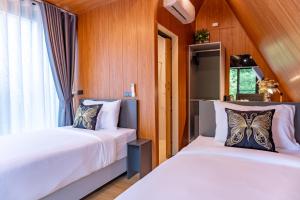 two beds in a room with wood paneling at The View A-Frame Cabin in Chiang Dao