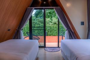 two beds in a room with a large window at The View A-Frame Cabin in Chiang Dao