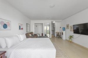 a white bedroom with a large bed and a living room at Maho Beach House - Studio - Beach Access in Maho Reef