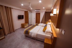 a hotel room with a bed and a television at Kuredhi Beach Inn in Maafushi