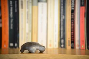 una pequeña estatuilla de elefante sentada en una mesa delante de los libros en Chez Pio, en Murten
