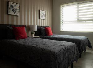 a bedroom with two beds with red pillows and a window at Casa Consulado Creta in Manuel F. Martínez