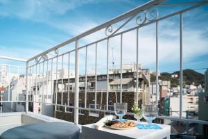 a table with a plate of food and wine glasses on a balcony at Casa Blanca Guesthouse in Nagasaki