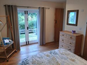 a bedroom with a bed and a dresser and a sliding glass door at Long Barn Wales in Monmouth