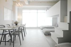 a dining room with a table and chairs and a bed at Casa Blanca Guesthouse in Nagasaki