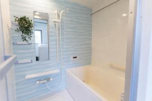 a white bathroom with a tub and a sink at The Emu Park Tomiyoshi in Kanie