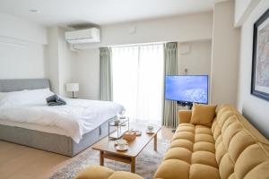 a living room with a couch and a bed at Hotel HIRAKU RYUKYU -STYLE- in Naha