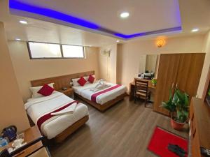 a hotel room with two beds and a desk at Hotel Maheshwor in Pashupatināth +48 photos