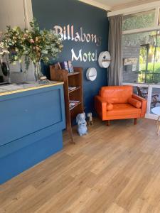 a living room with an orange chair and a blue wall at Billabong Motel in Gunnedah
